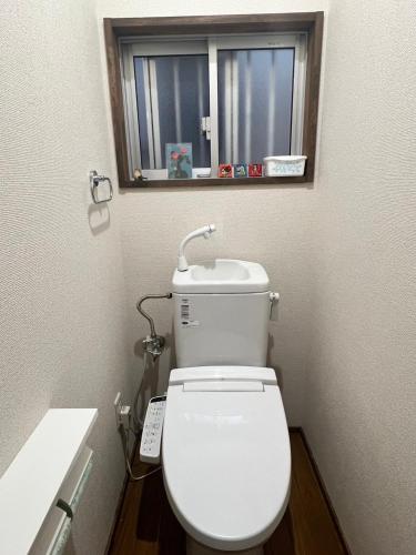 a white toilet in a bathroom with a window at La casa de Ikuchijima in Onomichi