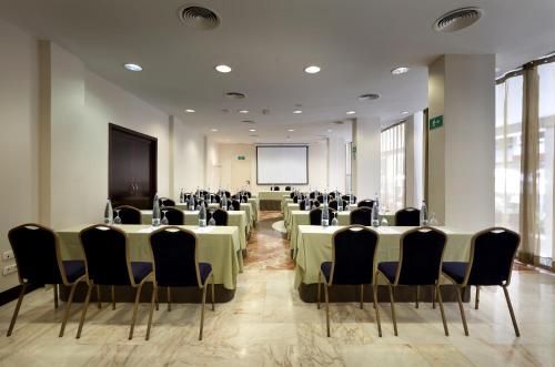 a conference room with tables and chairs and a screen at Exe Tartessos in Huelva