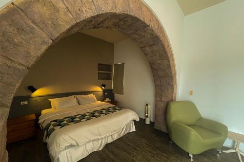 a bedroom with a bed and a green chair at 初嶼Meet in Hengchun