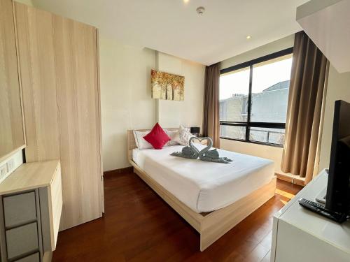 Un dormitorio con una cama blanca con almohadas rojas. en Cozy 2 Bedrooms - The Lago Nai Harn by AHP, en Rawai Beach