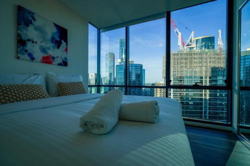 a bedroom with a white bed with a view of a city at Southbank 40 in Melbourne