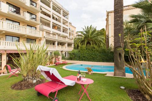 une chaise rose et une table devant un bâtiment dans l'établissement Sun Riviera Hotel, à Cannes