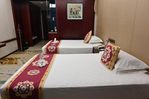a hotel room with two beds in a room at Dunhuang Hotel in Dunhuang