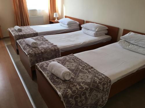 three beds in a hotel room with towels on them at Hotel Ferihegy in Vecsés