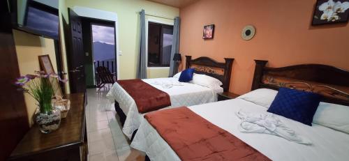 a hotel room with two beds and a window at Hotel El Tambor OASIS Antigua Guatemala in Antigua Guatemala