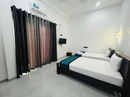 a bedroom with a bed and a television and curtains at Hotel Green Fall Kandyan in Ambatenna
