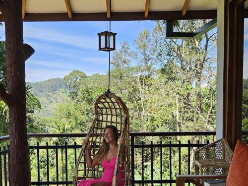 a woman sitting in a swing on a porch at Rawana Mount View - Ella in Bandarawela