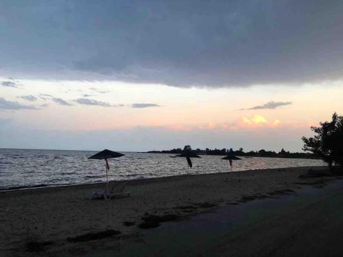 three people walking on the beach with umbrellas at Villa IVIA in Mándra