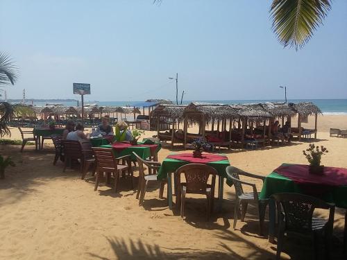 a group of tables and chairs on the beach at Hotel Universal Beach in Hikkaduwa