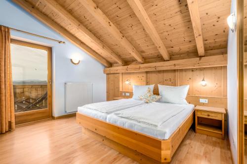 een bed in een kamer met een houten plafond bij Formsunhof in Siusi