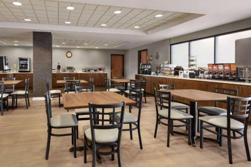 a restaurant with wooden tables and chairs and a counter at Wingate by Wyndham Denver Tech Center in Greenwood Village