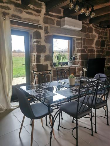 une salle à manger avec une table et des chaises en verre dans l'établissement Gite Le Fournil, à Saint-Pantaléon-de-Larche