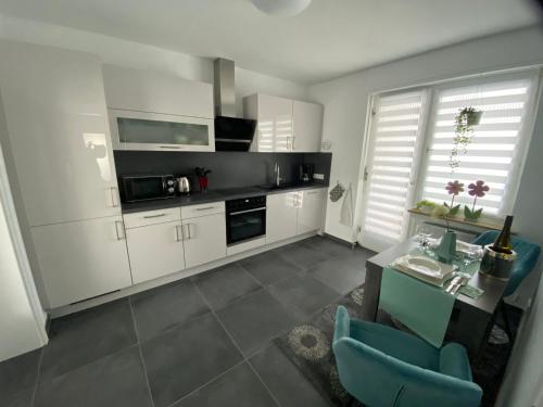 a kitchen with white cabinets and a table and blue chairs at Ferienwohnungen Schimsheimer Rhode in Olpe