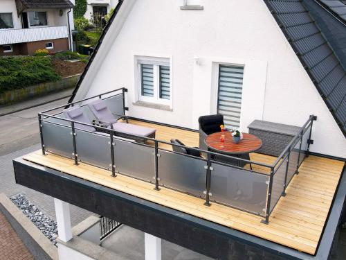 an elevated deck with a table and chairs on a house at Ferienwohnungen Schimsheimer Rhode in Olpe