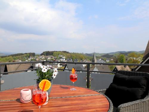 a wooden table with two wine glasses on a balcony at Ferienwohnungen Schimsheimer Rhode in Olpe