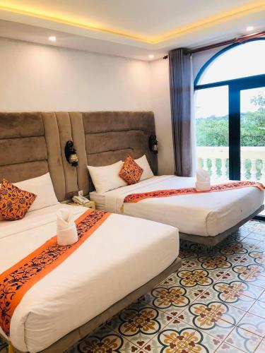 a hotel room with two beds and a window at Polin Hotel in Phumĭ Ândong Pring