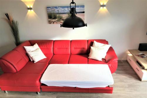 a red couch with white pillows in a living room at Fewo Kapitän James Cook Olpenitz in Kappeln