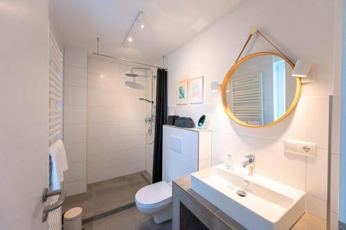 a bathroom with a sink and a toilet and a mirror at Lykke Lys in Heiligenhafen
