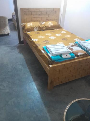 a bed with a wooden frame with a yellow comforter at Travellers Homestay in Silchar