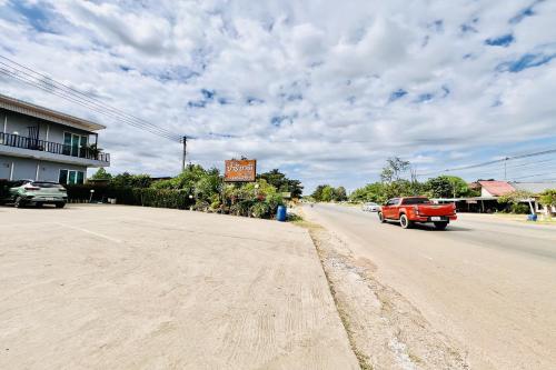 a red truck driving down a road with a sign at Parichat Bandung Hotel in Ban Dung