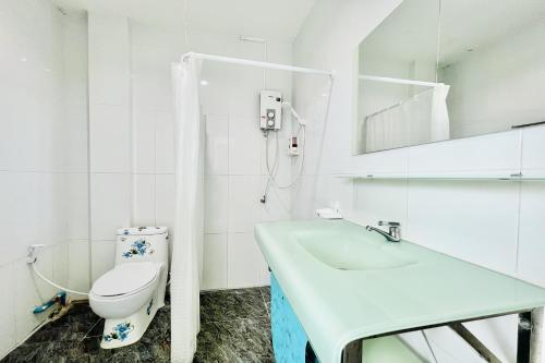 a white bathroom with a toilet and a sink at Parichat Bandung Hotel in Ban Dung
