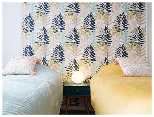 une chambre avec deux lits et un papier peint avec des plantes dans l'établissement Super appart entre Disney et Paris avec parking !, à Bailly-Romainvilliers