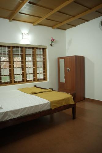 a bedroom with a bed and a wooden cabinet at RiverSoul Villa in North Paravur