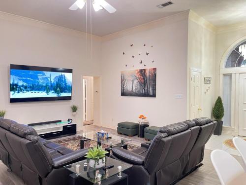 a living room with leather furniture and a flat screen tv at Charming 3-bedroom house near AT&T Stadium, Six Flag, DFW Airport in Bedford