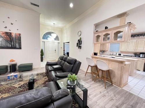 a living room with black leather furniture and a kitchen at Charming 3-bedroom house near AT&T Stadium, Six Flag, DFW Airport in Bedford