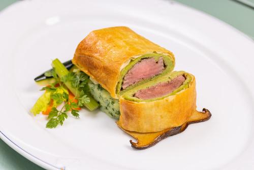 a sandwich with meat on a white plate at Vitalia Seehotel in Bad Segeberg