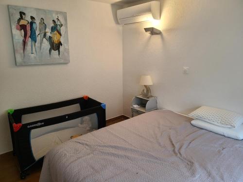 une chambre avec un lit et un tableau au mur dans l'établissement maison de famille, 5mn du vieux port, calme absolu, à La Ciotat