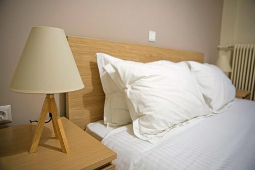 a bed with white pillows and a table with a lamp at Peaceful Renovated Apartment Near Lycabettus Hill in Athens