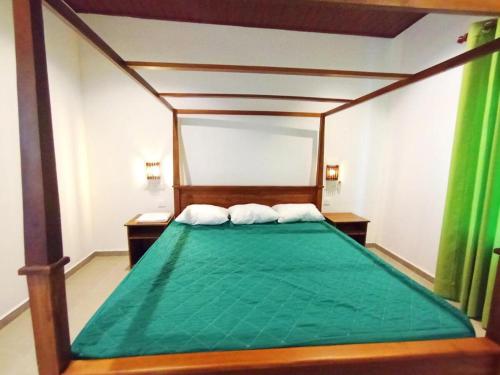 a bedroom with a green bed with two white pillows at Victoria Villa in Kamburugamuwa