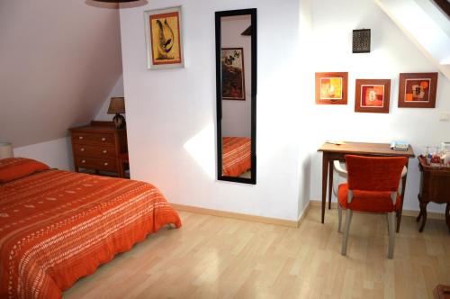 una camera da letto con un letto, un tavolo e uno specchio di La Maison Douce a Saint-Guyomard