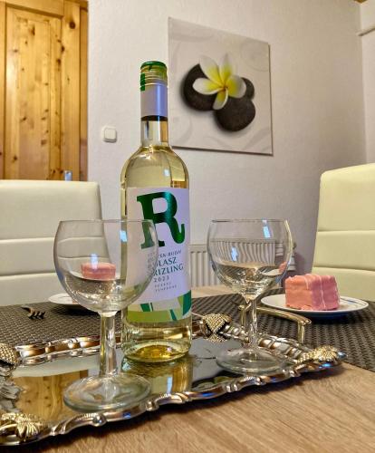 a bottle of wine sitting on a table with glasses at GANCZ APARTMAN in Sárvár
