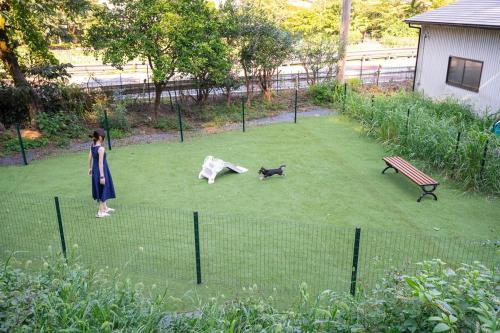a woman standing in a yard with a dog and a bench at ドッグラン付きのプライベート宿伊豆月ヶ瀬修善寺RVillage in Izu