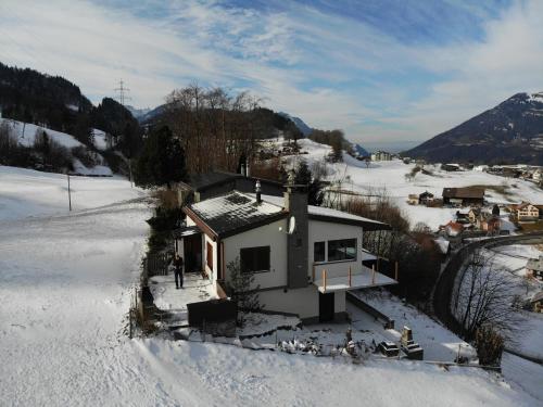 a house in the snow with a person standing next to it at Mürtschen Lodge in Filzbach