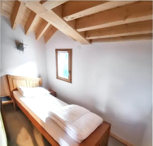 - une chambre dotée d'un lit avec des murs blancs et des plafonds en bois dans l'établissement Chalet spacieux à Saint-Sorlin-d'Arves avec options de loisirs, à Saint-Sorlin-dʼArves