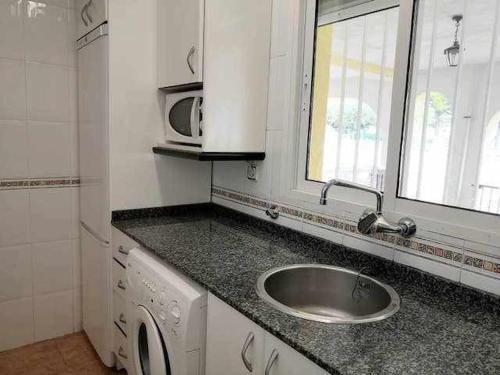 a kitchen with a sink and a microwave at A H RENTALS Columbra Amplio adosado a 100 mtrs playa Piscina Parking in Peñíscola