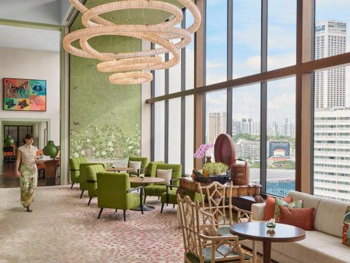 a woman walking through a lobby with a chandelier at Mandarin Oriental, Singapore in Singapore