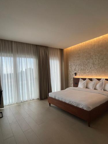 a bedroom with a large bed and large windows at NK Hotel Lagrace in Yaoundé