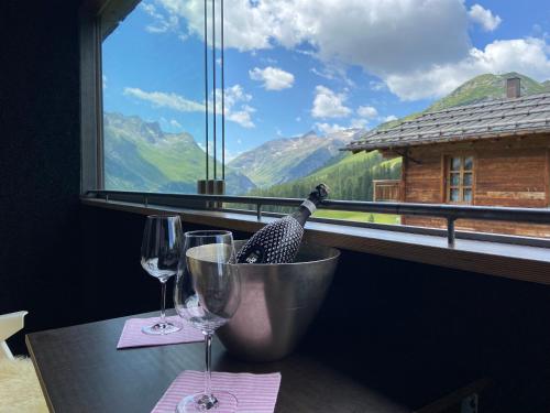 a table with two wine glasses and a window at Kar Design Appartements in Lech am Arlberg