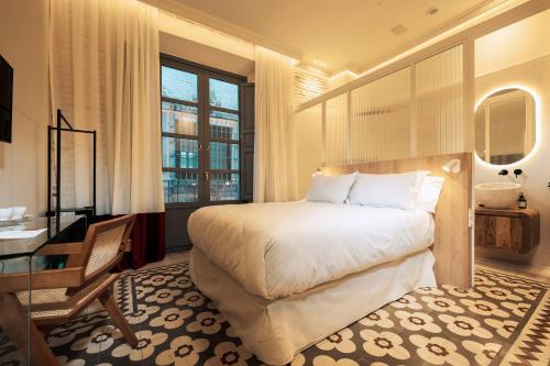 a bedroom with a bed and a desk and a window at Hotel Boutique Escudo del Carmen in Granada