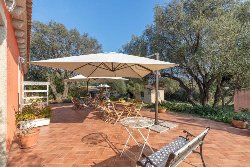 Un patio con sombrilla, mesas y sillas. en Domos Pintadas -Happy Rentals, en Rudalza