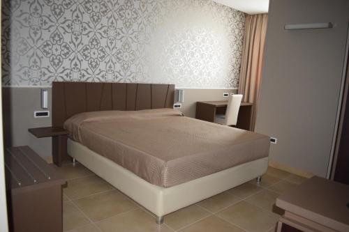 a bedroom with a large bed and a wall at Sunrise Hotel in Casoria