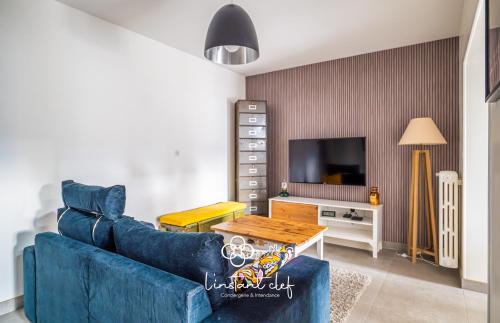 un salon avec un canapé bleu et une télévision dans l'établissement Évasion au Mans - Terrasse & Garage - L'Instant Clef, au Mans