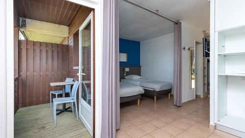 une chambre avec un lit, une table et une chaise dans l'établissement Villages Clubs du Soleil - SOUSTONS, à Soustons