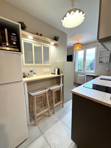 La cuisine est équipée d'un réfrigérateur et d'un comptoir avec tabourets. dans l'établissement La Cachette, à Dijon