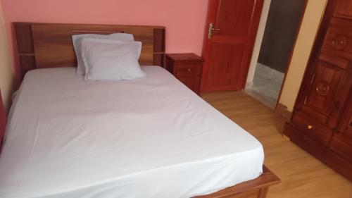 ManakambahinyにあるAppartement Fitahiana coupleの木製のヘッドボードが付いた白いベッドのある寝室