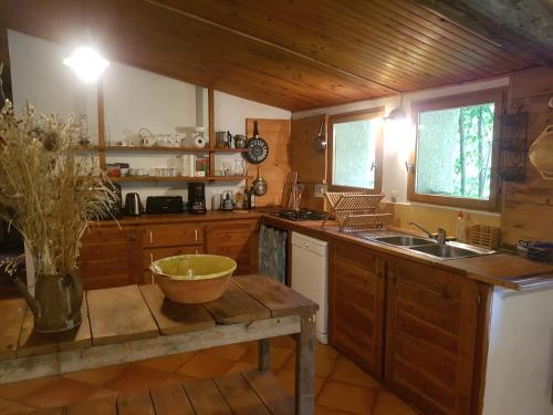 - une cuisine avec des placards en bois et un bol sur une table dans l'établissement Gîte du bout du monde La Bergerie, à Barrême